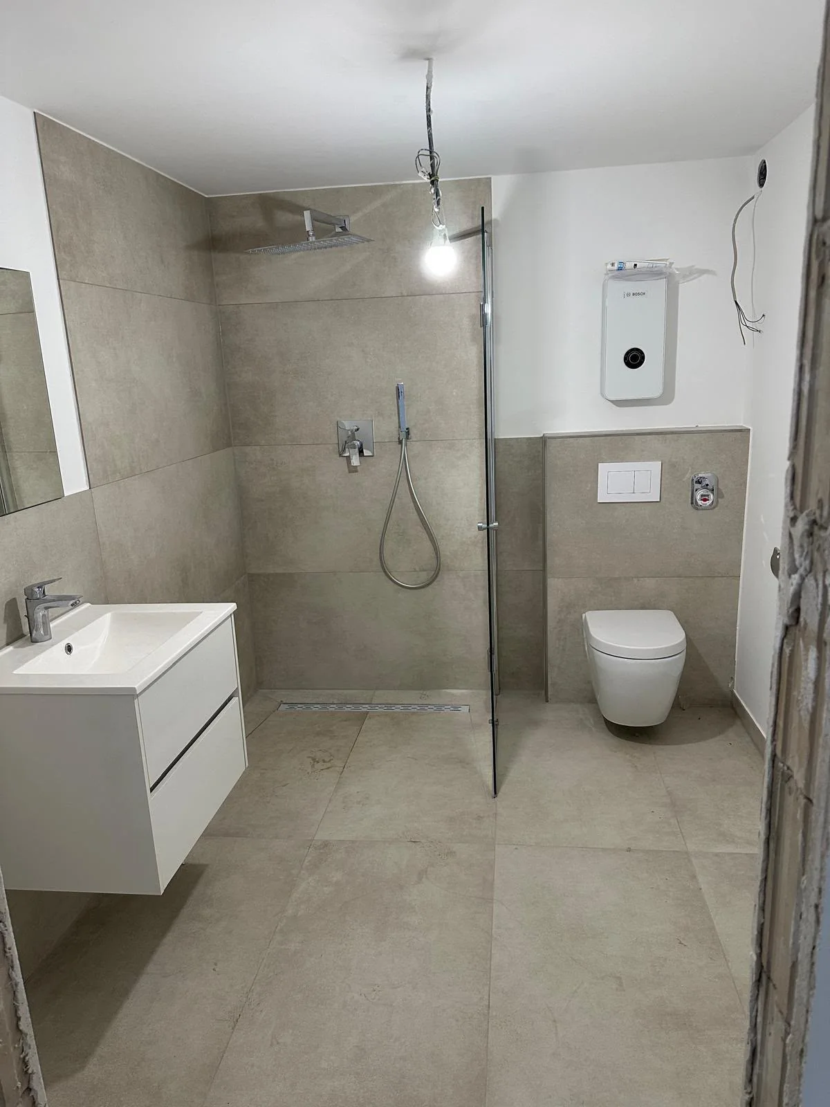Modernisiertes Badezimmer mit bodennaher Dusche, Waschtisch und WC